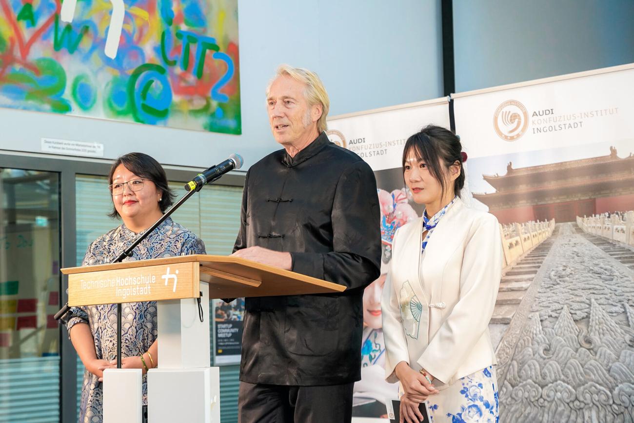 Prof. Dr. Peter Augsdörfer, Dr. Yueqi Wu und Jing Chen begrüßen die Gäste am Rednerpult