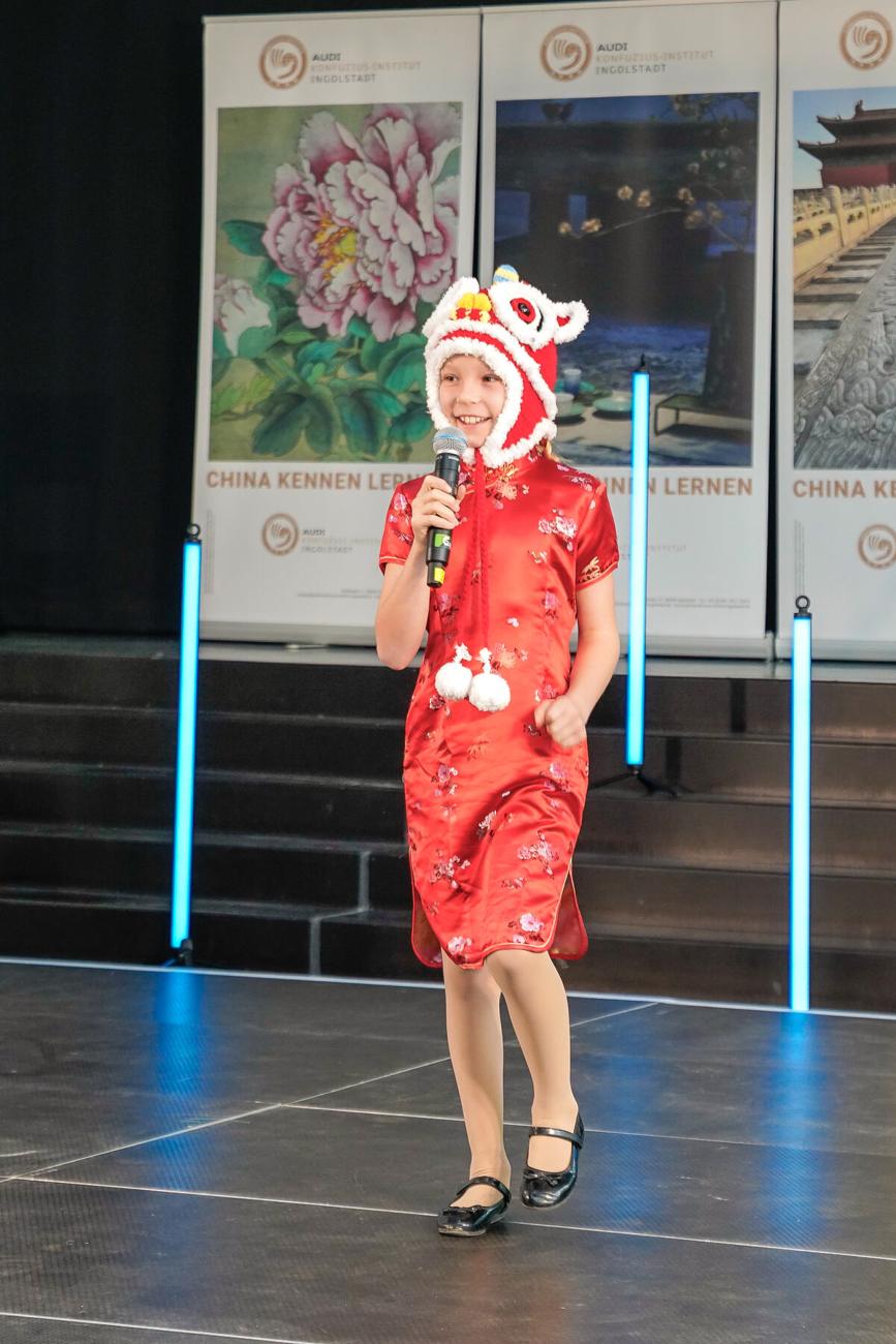 Annabelle Fenzel im roten Qipao am Mikrofon